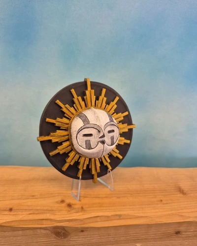 Figura decorativa de máscara solar de Esquie con rostro blanco y rayos dorados sobre fondo negro